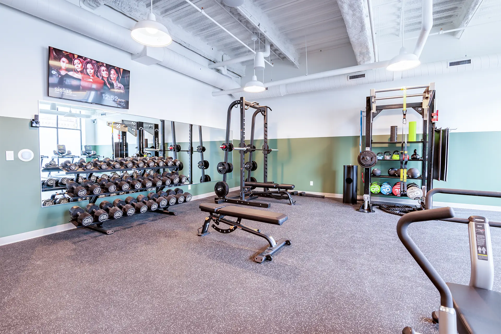 Interior view of a fitness center area with TV and weight training equipment.