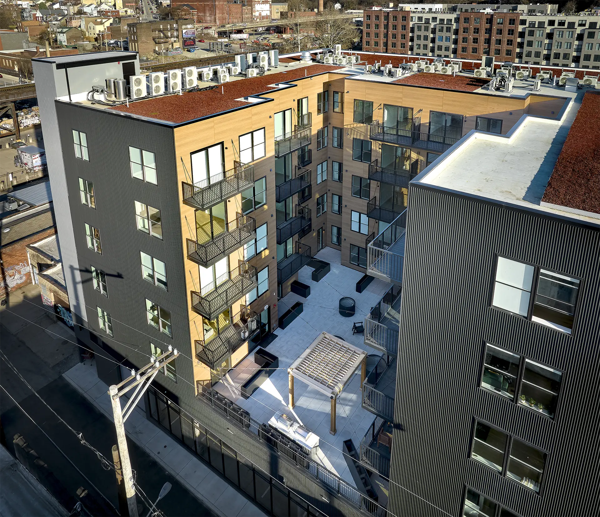 Aerial view of a contemporary apartment building with a shared courtyard, private balconies, and multiple residential levels.